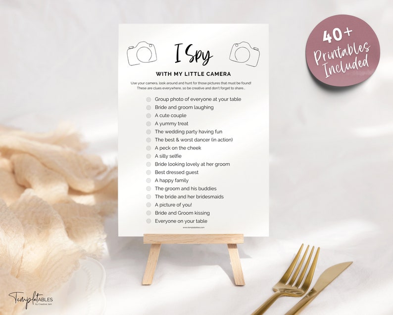 May include: A printable I Spy game with a camera theme. The game features a list of items to find at a wedding, such as a group photo, the bride and groom laughing, a cute couple, a yummy treat, and more.