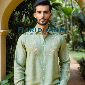 May include: A man wearing a light green linen shirt with floral embroidery. The shirt has a button-down collar and long sleeves. The text "PARIDHANIN Online store for Indian wedding outfits" is visible at the top of the image.
