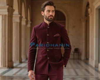 May include: A burgundy suit with a mandarin collar, featuring a matching pocket square. The suit has a tailored fit and is buttoned up. The image includes the text "PARIDHANIN Online store for indian wedding outfits".