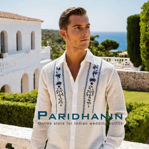 May include: A white linen shirt with blue embroidered floral designs. The shirt has a button-down collar and long sleeves. The text "PARIDHANIN Online store for Indian wedding outfits" is visible at the bottom of the image.