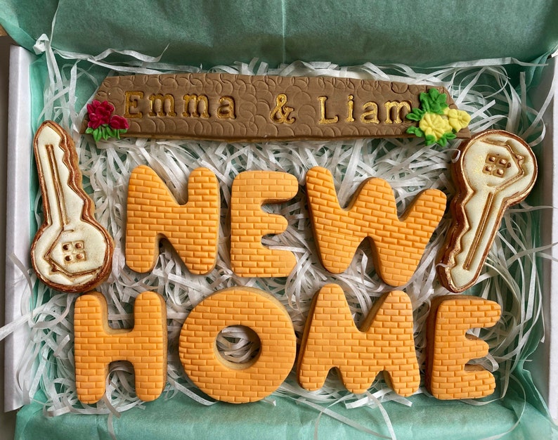 The Housewarming gift cookie box comes with a cookie representing a roof - this can be personalised.  Two house key cookies and brick textured seven letter cookies spelling New Home