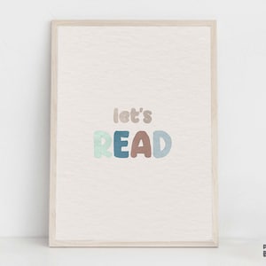May include: A framed print with a white background and the text "let's READ" in colorful, stylized letters. The letters are in shades of blue, green, and brown.