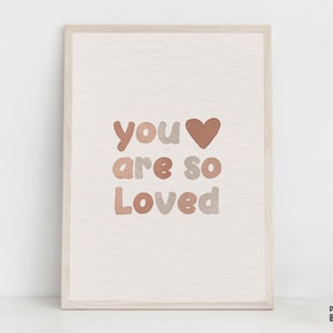 以下が含まれることがあります： 「you are so loved」というテキストが書かれた、茶色とベージュのカラーリングの印刷可能な壁掛けアートプリント。テキストの中央にハートマークがあります。