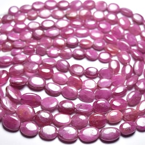 Peut inclure: Un brin de perles ovales en pierres précieuses roses. Les perles sont lisses et polies, avec un léger éclat.