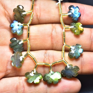May include: A strand of gold beads with labradorite gemstone flower charms. The gemstones are iridescent with shades of green, blue, and black.