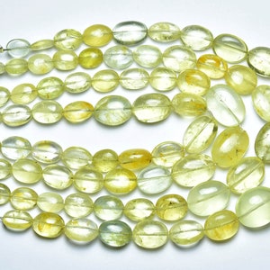 May include: A strand of oval-shaped, translucent green and yellow gemstone beads. The beads are strung on a silver wire.