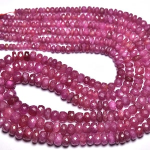 Könnte beinhalten: Eine Strähne aus rosa Rubinperlen, facettiert und poliert, auf einem Faden aufgereiht. Die Perlen haben einen Durchmesser von etwa 4 mm und eine leicht unregelmäßige Form.