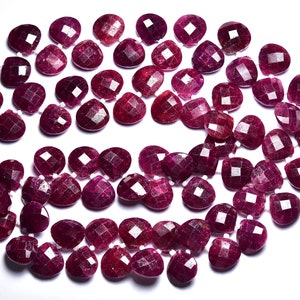 Può includere: Una collana di perle di pietra preziosa sfaccettate di colore rosso rubino a forma di lacrima. Le perle sono infilate su un filo bianco e sono disposte in un motivo sciolto e fluido.