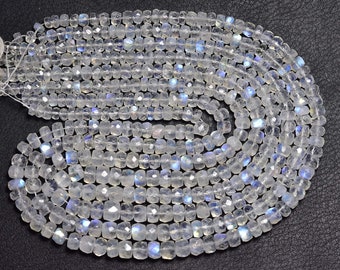 May include: A strand of white moonstone beads with a iridescent sheen. The beads are faceted and have a square shape.