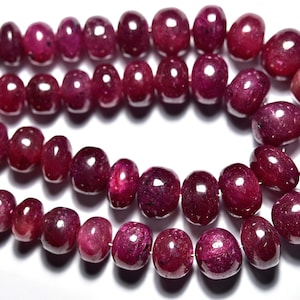 Może przedstawiać: Szereg głębokoczerwonych koralików rubinowych, każdy koralik jest okrągły i lekko owalny. Koraliki są nawleczone na cienki drut i ułożone w podwójnym rzędzie.