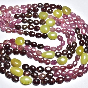 May include: A strand of oval-shaped gemstone beads in shades of pink, red, and yellow. The beads are strung on a clear thread and are arranged in a circular pattern.