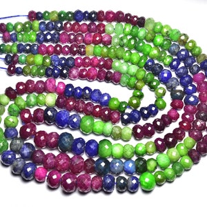 May include: A strand of faceted gemstone beads in shades of green, pink, and blue. The beads are strung on a thin cord and are arranged in a circular pattern.