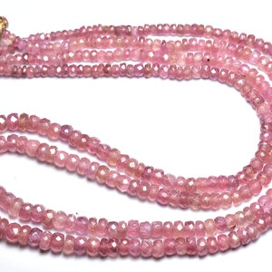Op de afbeelding: Een streng roze edelsteen kralen, waarschijnlijk roze saffieren, met een gefacetteerde, licht onregelmatige vorm. De kralen zijn geregen op een dun koord en zijn ongeveer 4 mm in diameter.