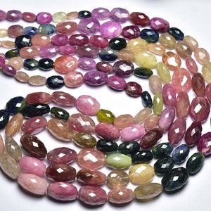 May include: A strand of multi-coloured faceted gemstone beads. The beads are oval shaped and have a variety of colours, including pink, green, blue, and yellow.