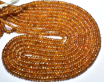 May include: A strand of orange gemstone beads. The beads are faceted and have a slightly irregular shape. The beads are strung on a clear thread.