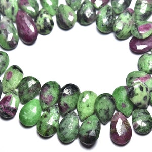 K&ouml;nnte beinhalten: Eine Str&auml;hne aus gr&uuml;nen, rosa und schwarzen Edelsteinperlen. Die Perlen sind birnenf&ouml;rmig und haben eine facettierte Oberfl&auml;che.