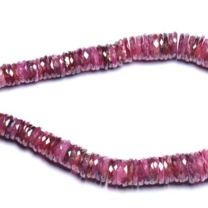 Op de afbeelding: Een streng roze edelsteen kralen, elke kraal is gefacetteerd en heeft een licht onregelmatige vorm. De kralen zijn geregen op een dunne draad en zijn klaar om te gebruiken voor het maken van sieraden.