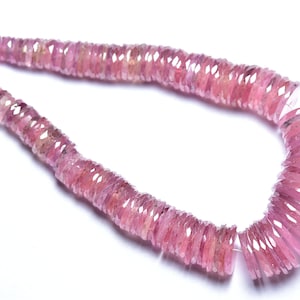 May include: A strand of pink gemstone beads, each bead is faceted and shaped like a small, flat disc. The beads are strung on a clear thread and are arranged in a loose, flowing pattern.