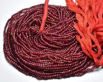 May include: A strand of red gemstone beads, likely garnet, with a faceted finish. The beads are strung on a red thread and are ready for jewelry making.