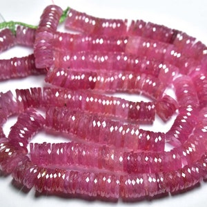 May include: A strand of pink ruby beads, each bead is faceted and has a rectangular shape. The beads are strung on a clear thread.