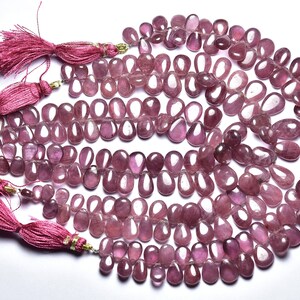 Può includere: Una collana di perle di pietra preziosa rosa, a forma di goccia, infilate su un filo sottile. Le perle sono disposte in un motivo circolare, con diversi fili sovrapposti. Le perle sono di colore rosa chiaro, con un leggero luccichio.