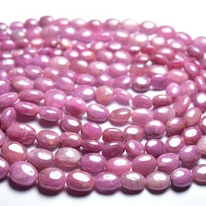 Peut inclure: Un brin de perles ovales de pierres précieuses roses. Les perles ont une finition lisse et polie et un léger éclat.