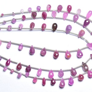 May include: A strand of pink and purple gemstone beads in a teardrop shape. The beads are strung on silver wire and are approximately 10mm in size.