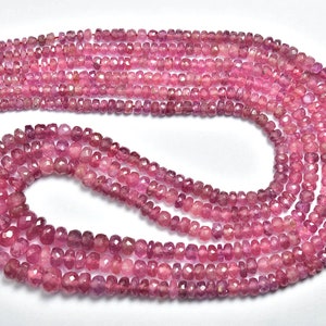 May include: A strand of pink gemstone beads, faceted and strung on a red thread. The beads are pink and have a slightly irregular shape.