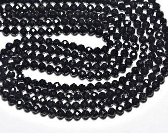 May include: Close-up of multiple strands of black faceted beads. The beads are small, with many facets that catch the light, creating a sparkling effect. The beads are strung together, ready for jewelry making.