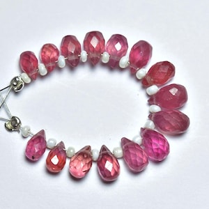 May include: A strand of pink ruby gemstone beads with faceted drops, interspersed with white pearl beads. The beads are strung on a silver wire.