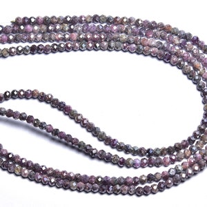 May include: A strand of faceted pink and gray gemstone beads. The beads are small and round, and they are strung on a clear thread.