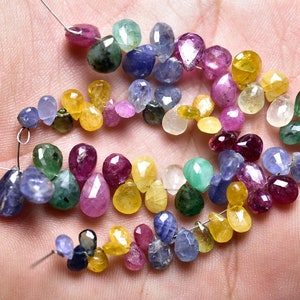 May include: A strand of colorful gemstone beads, including blue, green, yellow, and red, in a teardrop shape. The beads are strung on a wire and are ready to be used for jewelry making.