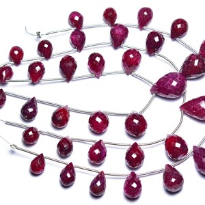 Peut inclure: Un brin de perles de rubis en forme de goutte. Les perles sont facettées et ont une couleur rouge foncé. Les perles sont enfilées sur un fil d'argent.