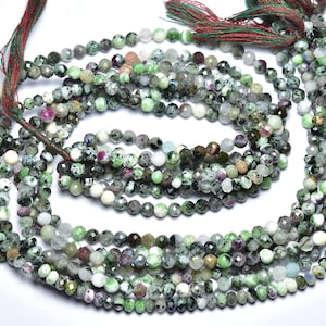 May include: A strand of green, white, and black gemstone beads. The beads are faceted and have a speckled appearance. The strand is approximately 18 inches long.
