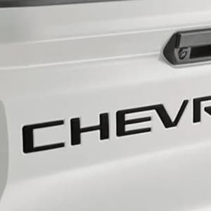 May include: A white truck tailgate with a black "CHEVROLET" logo and a black handle.