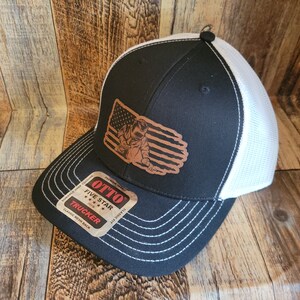 May include: Black and white trucker hat with a brown leather patch featuring a welder in front of an American flag. The patch says "OTTO FIVE STAR TRUCKER".