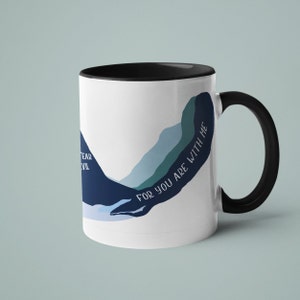 May include: White ceramic mug with a black rim and handle. The mug features a blue and green abstract design with the text "For you are with me".