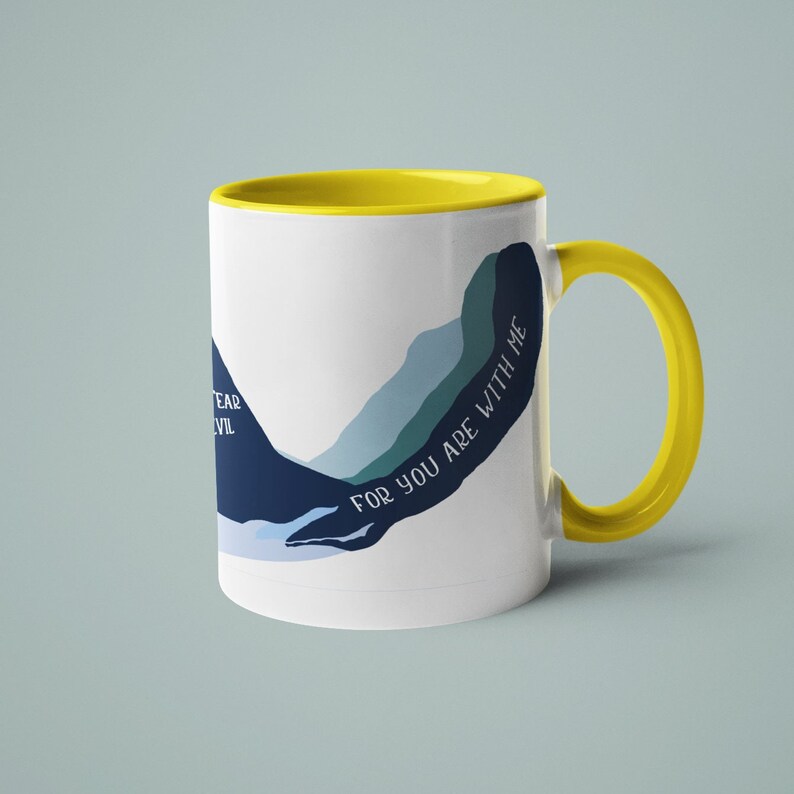 May include: White ceramic mug with a yellow rim and handle. The mug features a blue and green abstract design with the text "For you are with me".