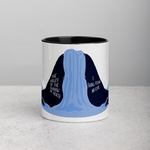 May include: White ceramic mug with a black rim and handle. The mug features a blue and black illustration of a waterfall with the text "The Valley of the Shadow of Death" on the left side and "I Shall Fear No Evil" on the right side.