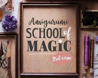 Peut inclure: Une affiche encadrée avec le texte "Amigurumi School of Magic 3rd term" en lettres noires sur un fond brun clair. L'affiche est entourée de divers articles de bricolage, notamment de la laine, des cristaux et une petite boîte en bois.
