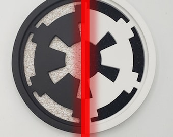 May include: A black and white circular coaster with the Star Wars Imperial symbol split down the middle. The left side is black with a white symbol and the right side is white with a black symbol.