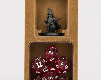 May include: A rectangular gold-colored storage case with two clear windows. The top compartment holds a small gray wizard figurine. The bottom compartment contains a set of translucent red polyhedral dice with white numbers.