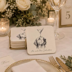 Puede incluir: Posavasos cuadrados de color blanquecino con una ilustración en blanco y negro de un perro con una copa de martini equilibrada sobre su cabeza. Los posavasos tienen el texto "Mr and Mrs Johnstons" escrito en ellos. Un juego de posavasos está en un soporte de metal dorado.