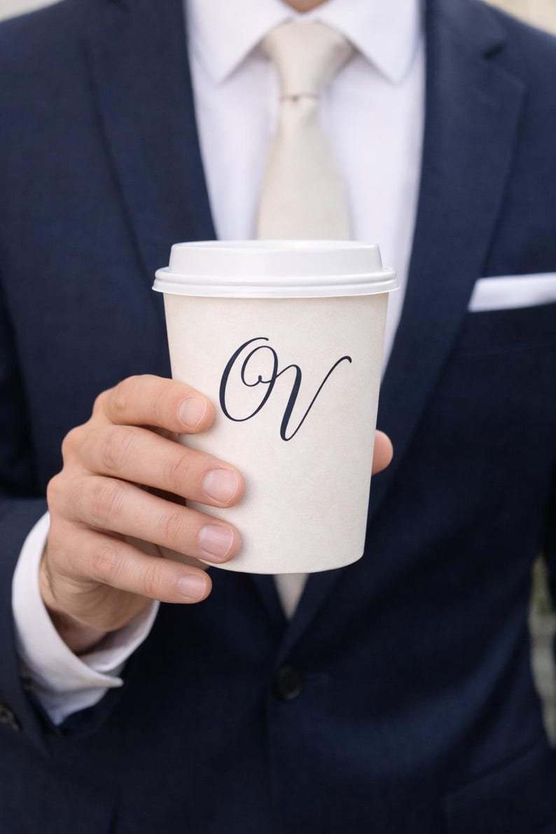 May include: A white ceramic mug with a black handle and the text "But First, Coffee" in a bold, black font. The mug sits on a white surface, showcasing its clean design.