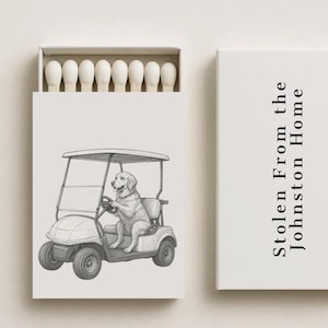 May include: A matchbox set with a whimsical illustration of a dog driving a golf cart. The box on the right has the text "Stolen From the Johnston Home". The matches are white.