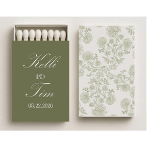 May include: A matchbox with a green cover, displaying the names "Kelli" and "Tim" and the date "05.22.2026" in cursive script. The matchbox is open, showing white match heads. The other side has a floral design.