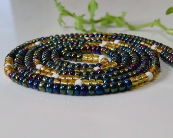 Puede incluir: Un collar de cuentas multicolores con cuentas iridiscentes azules, verdes, doradas y blancas. El collar está enrollado en forma de espiral.