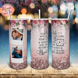 May include: A 20 ounce stainless steel tumbler with a pink floral design and glitter accents. The tumbler features two photos of a couple and the text "Your life was a blessing, a treasure you are loved beyond words & missed beyond measure".