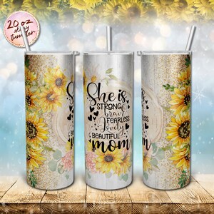 May include: A 20 ounce stainless steel tumbler with a white woodgrain background and a sunflower design. The tumbler has a black text overlay that reads "She is strong, brave, fearless, lovely, beautiful mom".