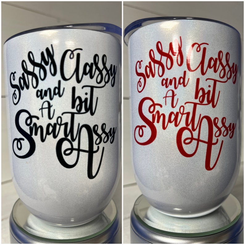 May include: Two white tumblers with a glitter finish. One tumbler has black lettering that reads "Sassy Classy and a bit Smart Assy". The other tumbler has red lettering that reads "Sassy Classy and a bit Smart Assy".